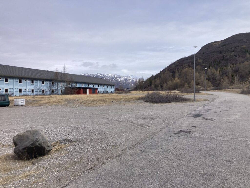 Åben grusplads med bygninger og fjeld